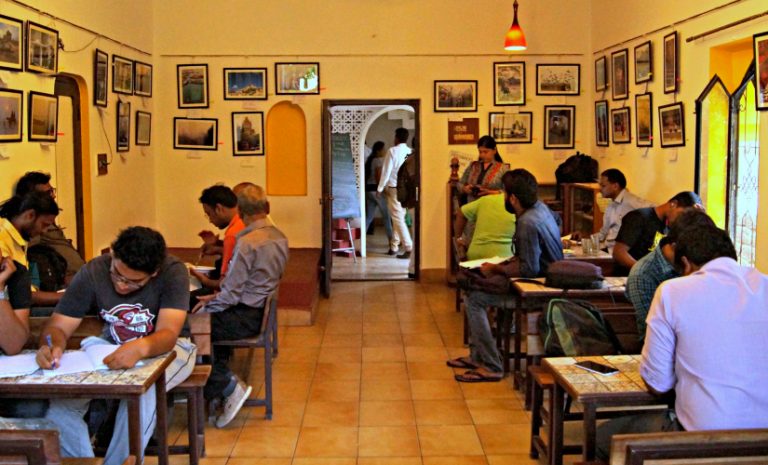 The Lamakaan cafe: people at small tables in a yellow room hung with framed photographs
