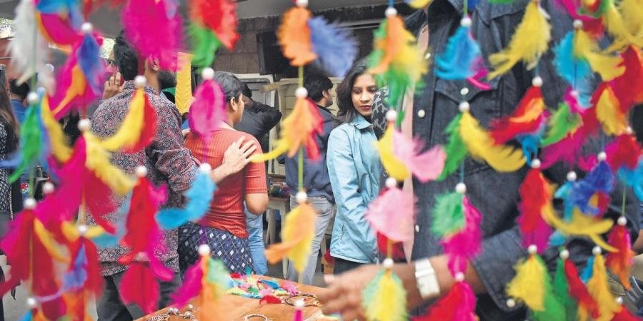 People among strings of bright feathered decorations